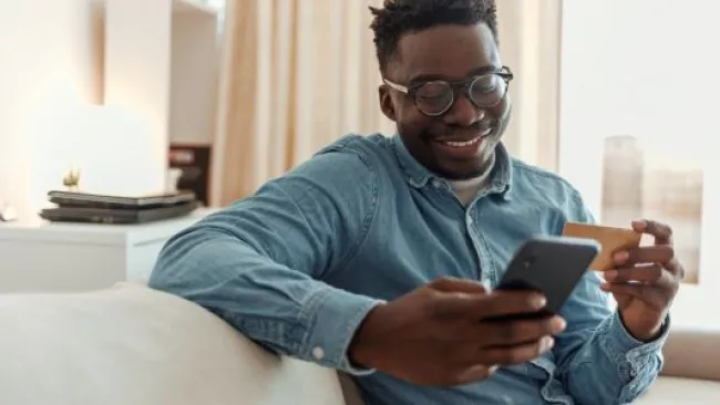 A guy smiling while doing something on his phone