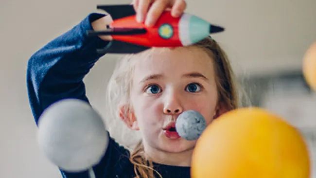 A young girl playing with a spaceship