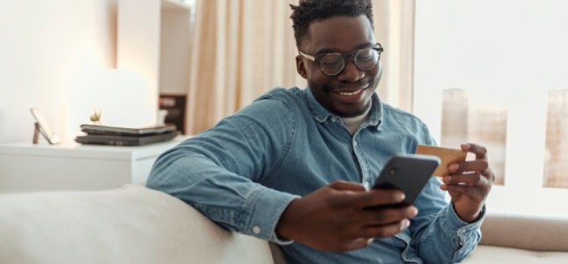 A guy smiling while doing something on his phone