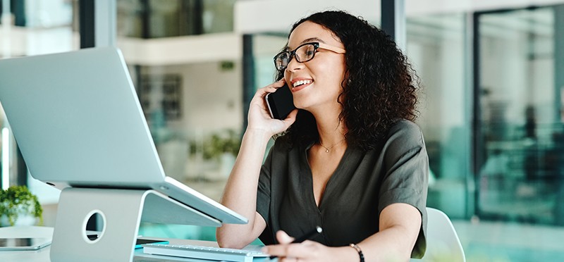 Woman working on laptop and talking on phone