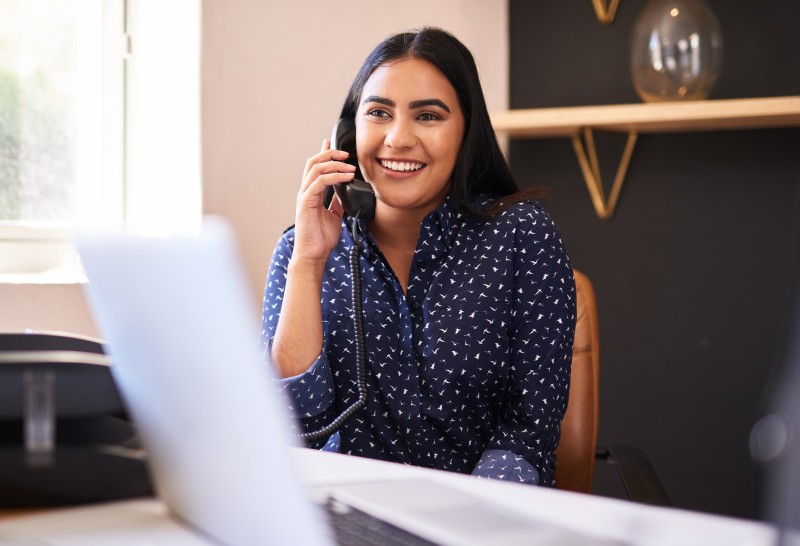 Woman smiling and holding phone at desk